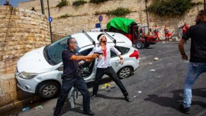 An Israeli policeman fends off an angry mob, after they swarmed an Israeli motorist, pelting his car with stones and driving him off the road, outside Jerusalem's Old City, May 10, 2021. Photo by Olivier Fitoussi/Flash90.