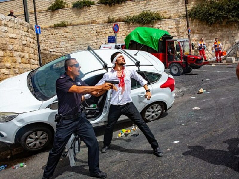 An Israeli policeman fends off an angry mob, after they swarmed an Israeli motorist, pelting his car with stones and driving him off the road, outside Jerusalem's Old City, May 10, 2021. Photo by Olivier Fitoussi/Flash90.