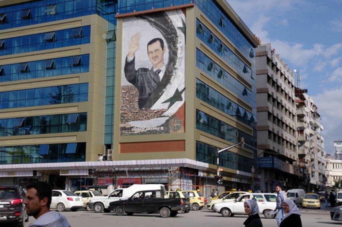 A mural featuring Syrian President Bashar Assad in Latakia, Syria. Credit: Emesik via Wikimedia Commons.