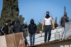 Palestinians with gas cylinders stand on a rooftop of a house being evacuated by Israeli special forces, in the East Jerusalem neighborhood of Sheikh Jarrah, on January 17, 2022. Photo by Yonatan Sindel/Flash90