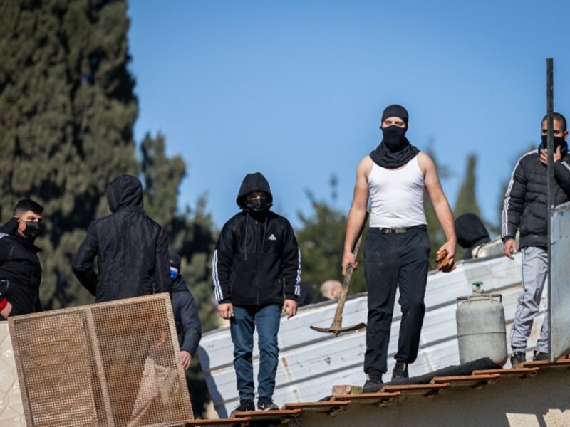 Palestinians with gas cylinders stand on a rooftop of a house being evacuated by Israeli special forces, in the East Jerusalem neighborhood of Sheikh Jarrah, on January 17, 2022. Photo by Yonatan Sindel/Flash90