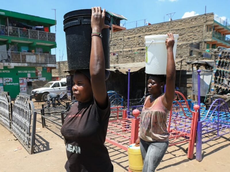 Women carry water buckets filled with water after fetching it from one of the illegal freshwater points in Mathare slum. EPA-EFE/Daniel Irungu