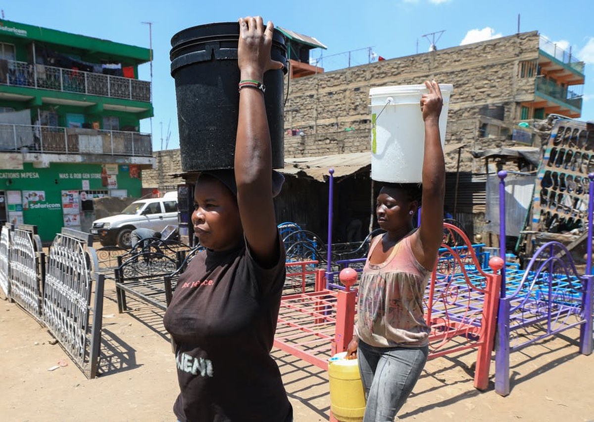 Women carry water buckets filled with water after fetching it from one of the illegal freshwater points in Mathare slum. EPA-EFE/Daniel Irungu