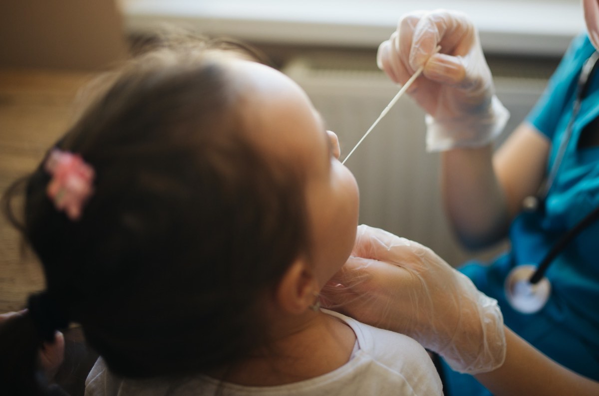 Doctor holds swab for mucus sample from kid nose or mouth closeup back view. Nenad Stojkovic, flickr https://creativecommons.org/licenses/by/2.0/